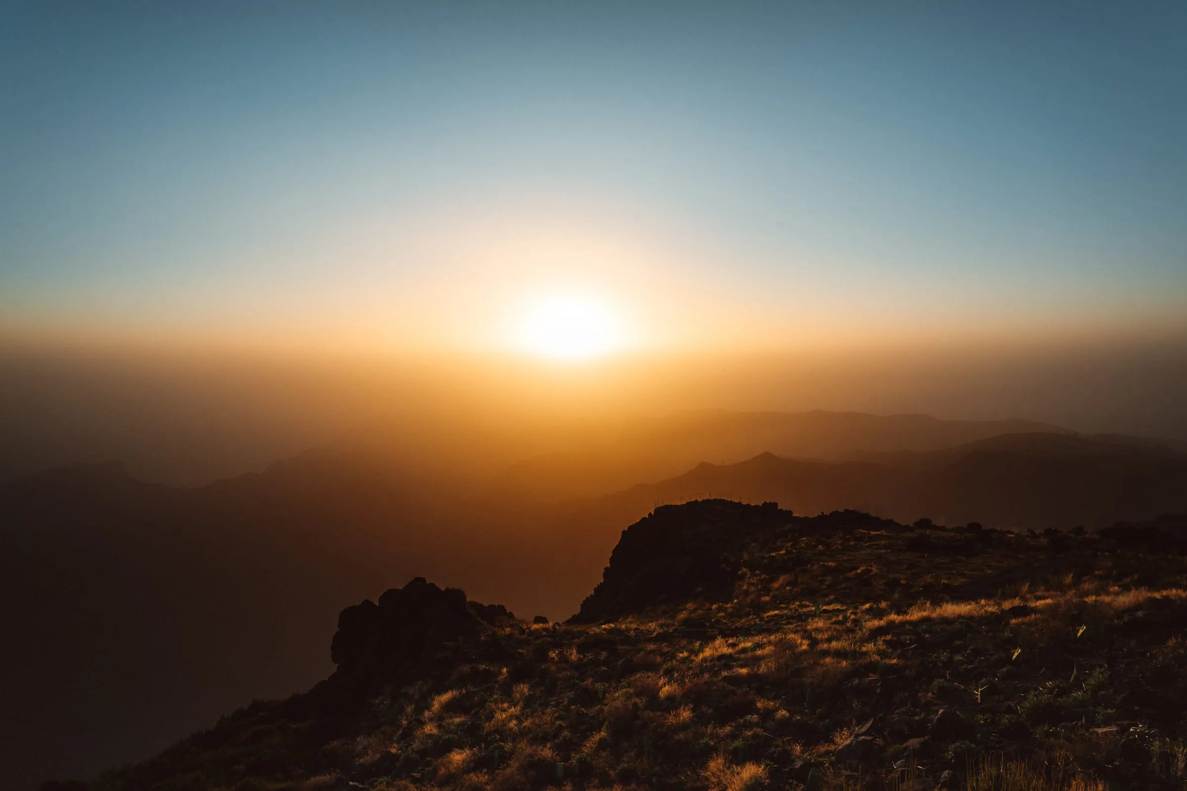 Slunce vycházející v oparu nad horami z Pico do Arieiro