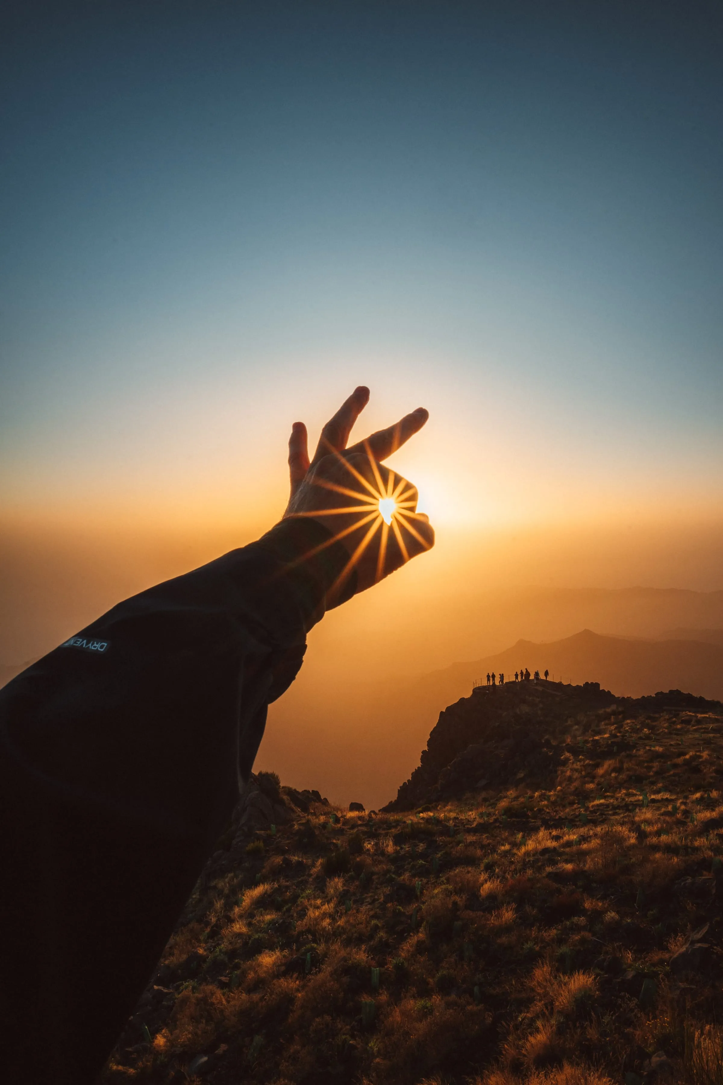 Ruka rámující vycházející slunce na Pico do Arieiro