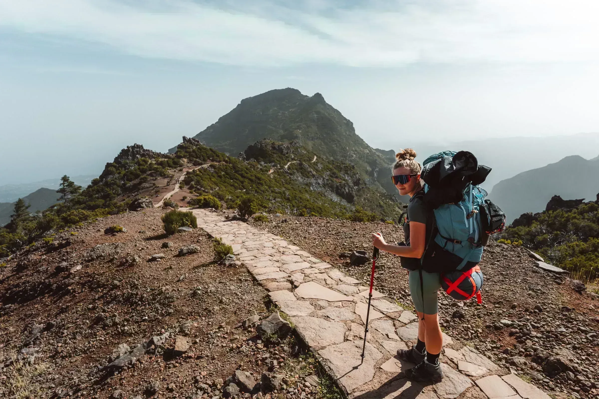 Trekařka s krosnou na kamenné stezce po hřebeni k Pico do Jorge