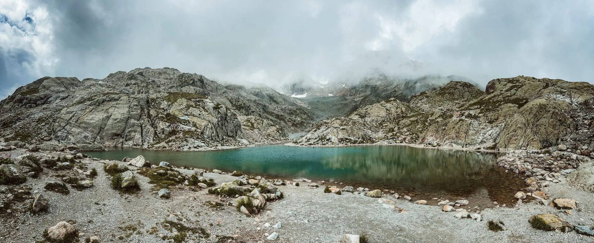 Horské jezero mezi skalami pod mraky