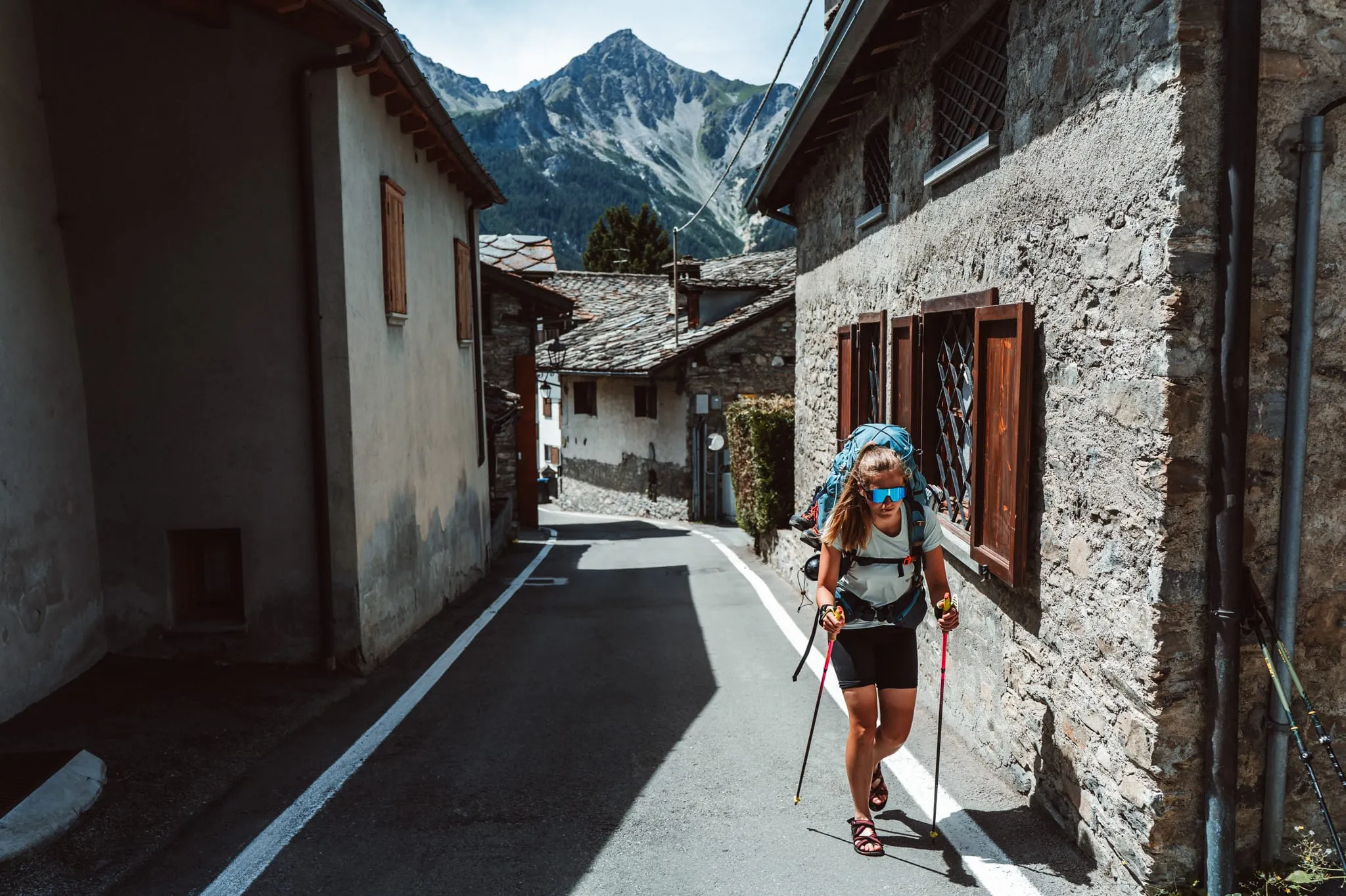 Trekařka v sandálech prochází kamennou vesnicí u Courmayeuru