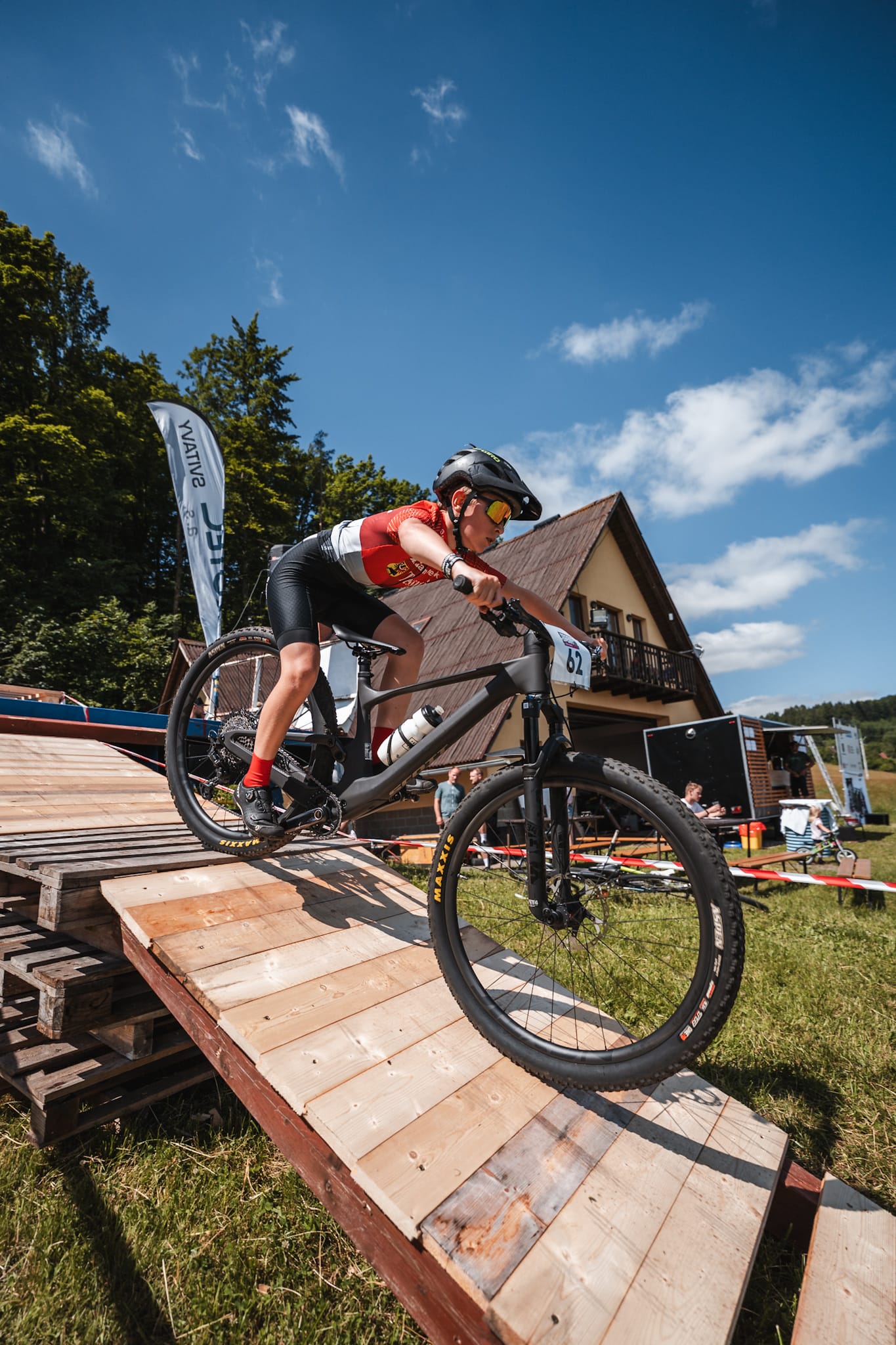Mladý závodník na horském kole přejíždí dřevěnou překážku z palet na cyklistickém závodě
